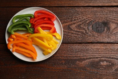 Photo of Cut colorful bell peppers on wooden table, top view. Space for text