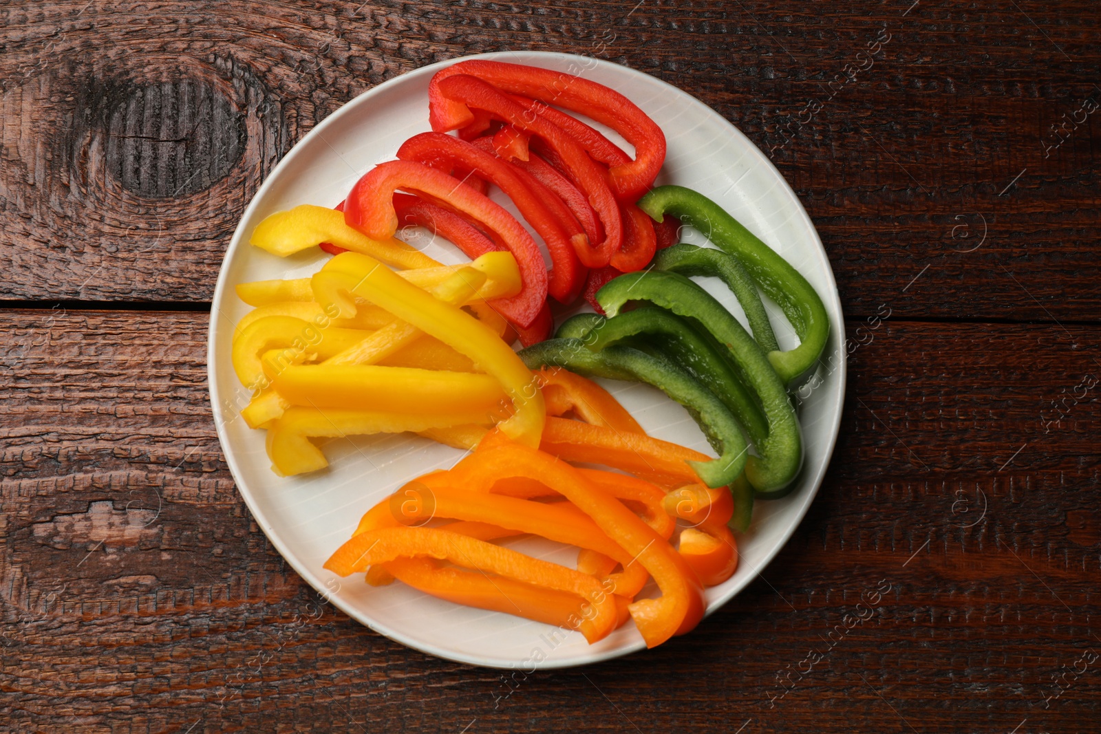 Cut colorful bell peppers on wooden table, top view Photo of Cut colorful bell peppers on wooden table, top view
