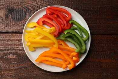 Photo of Cut colorful bell peppers on wooden table, top view