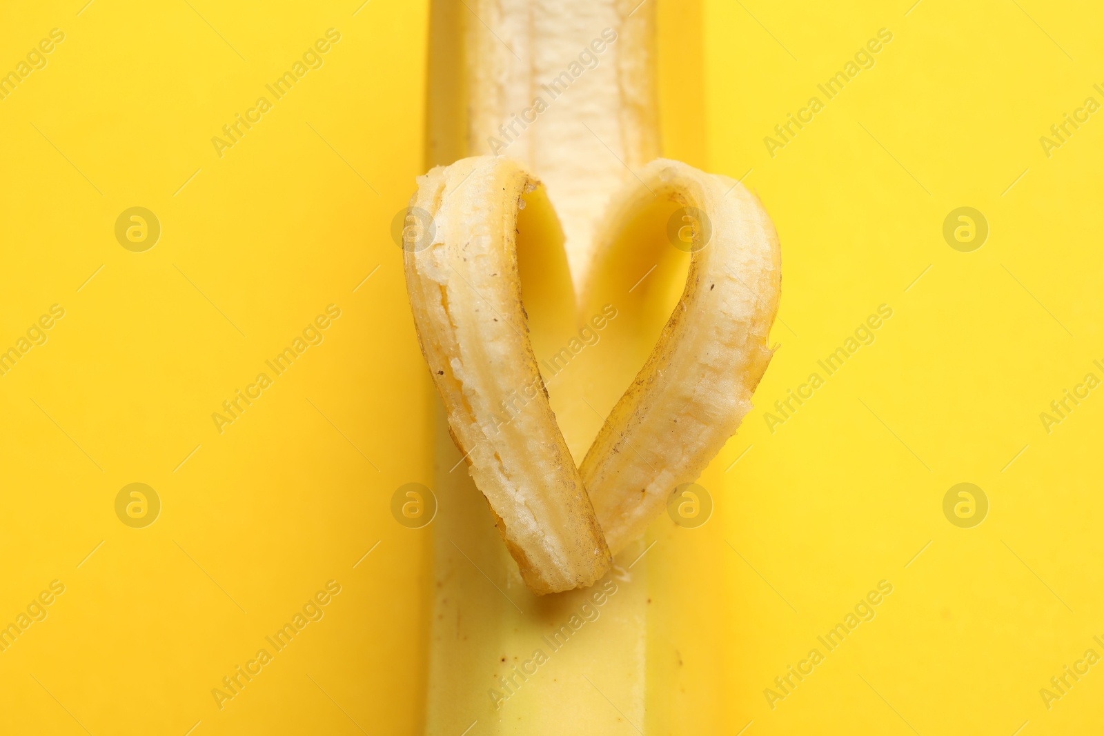Banana with heart made of peel on yellow background, closeup Photo of Banana with heart made of peel on yellow background, closeup
