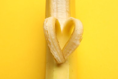 Photo of Banana with heart made of peel on yellow background, closeup