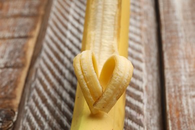 Photo of Banana with heart made of peel on wooden table, closeup