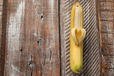 Photo of Banana with heart made of peel on wooden table, top view. Space for text