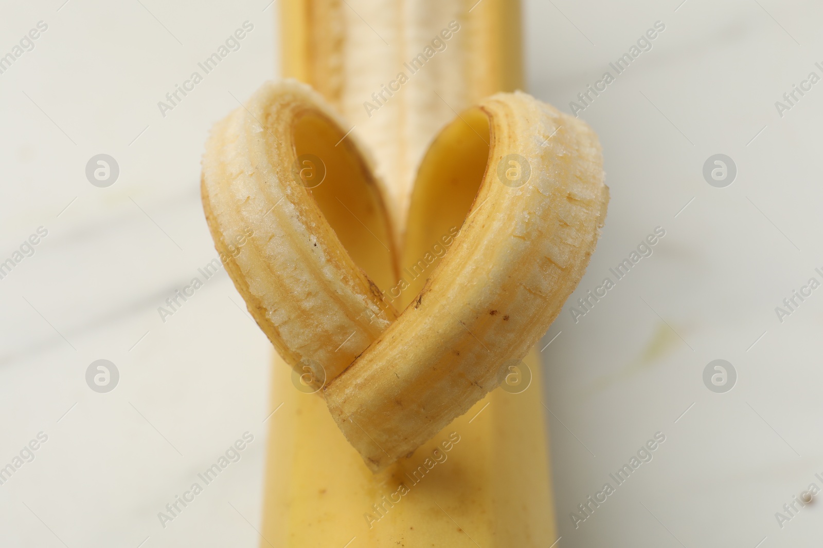 Banana with heart made of peel on white table, closeup Photo of Banana with heart made of peel on white table, closeup