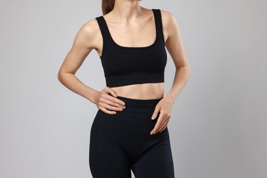 Photo of Beautiful woman with flat belly on gray background, closeup