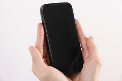 Photo of Woman holding smartphone with blank screen on white background, closeup. Mockup for design