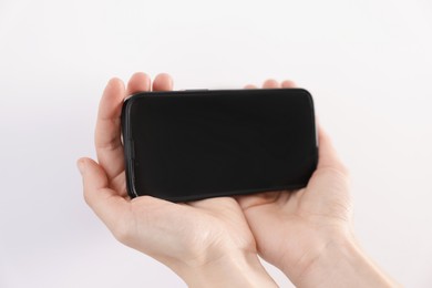 Photo of Woman holding smartphone with blank screen on white background, closeup. Mockup for design