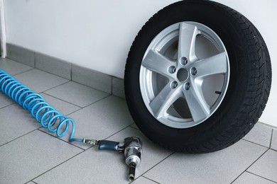 Photo of New tire and impact wrench gun at car service