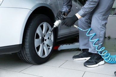 Photo of Mechanic changing tire at car service, closeup