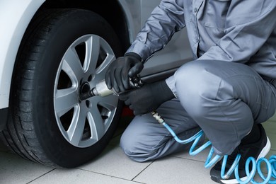 Photo of Mechanic changing tire at car service, closeup