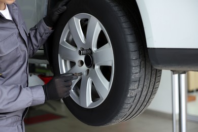 Photo of Mechanic changing tire at car service, closeup