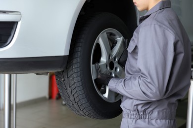 Photo of Mechanic changing tire at car service, closeup