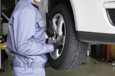 Photo of Mechanic changing tire at car service, closeup