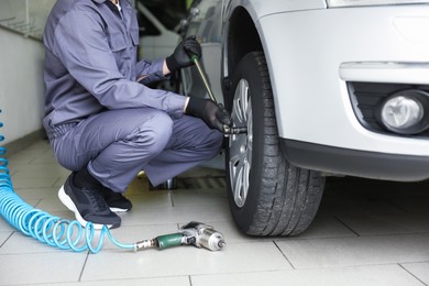 Photo of Mechanic changing tire at car service, closeup