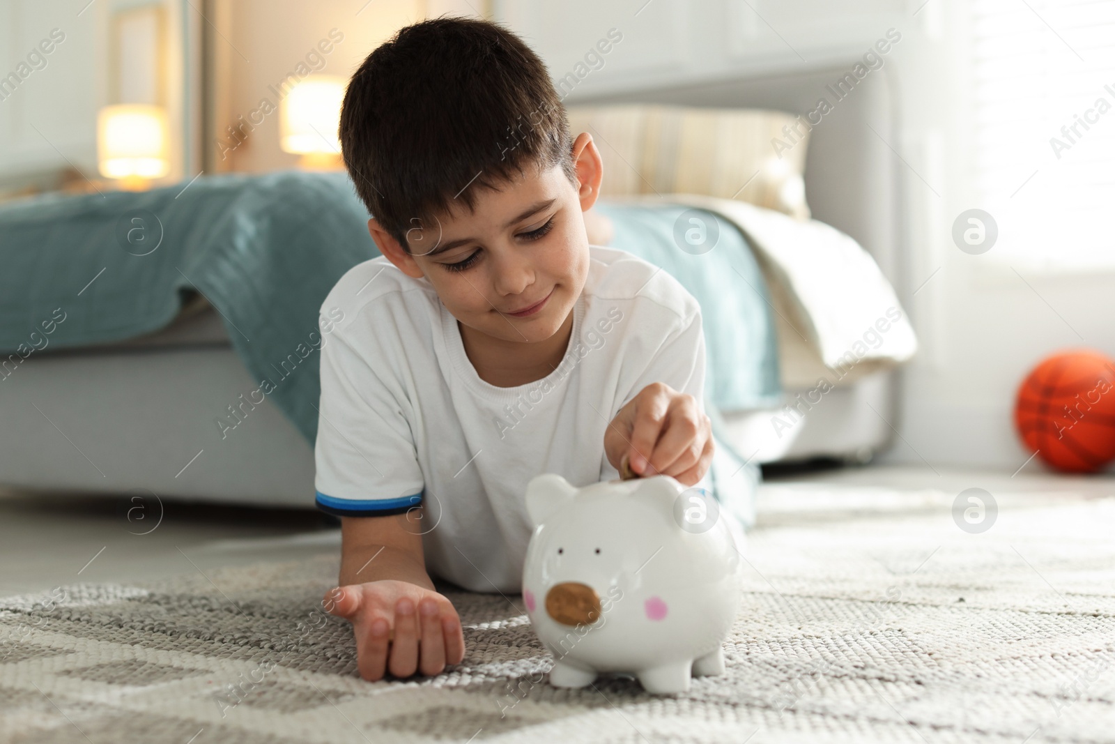 Photo of Boy putting pocket money into piggybank at home