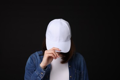 Photo of Young woman wearing stylish white baseball hat on black background