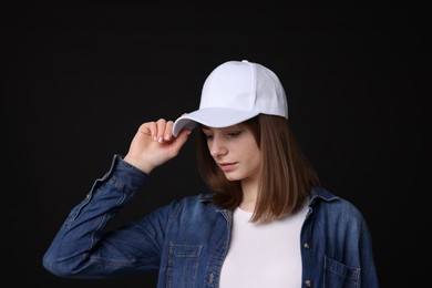 Photo of Young woman wearing stylish white baseball hat on black background