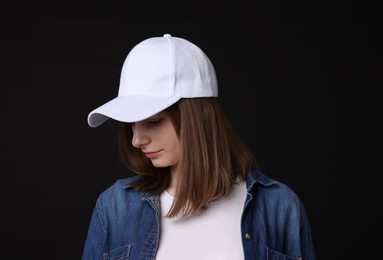 Photo of Young woman wearing stylish white baseball hat on black background