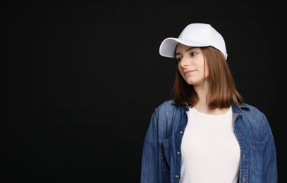 Photo of Young woman wearing stylish white baseball hat on black background, space for text