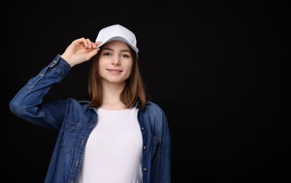 Photo of Young woman wearing stylish white baseball hat on black background, space for text