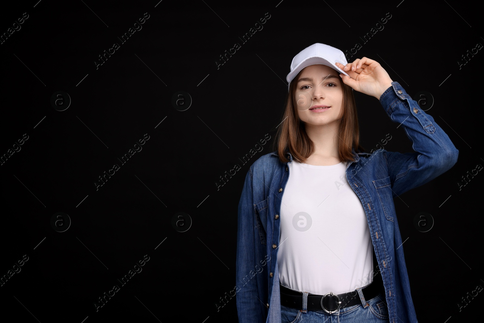 Young woman wearing stylish white baseball hat on black background, space for text Photo of Young woman wearing stylish white baseball hat on black background, space for text