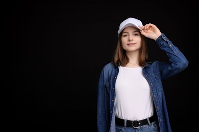 Photo of Young woman wearing stylish white baseball hat on black background, space for text