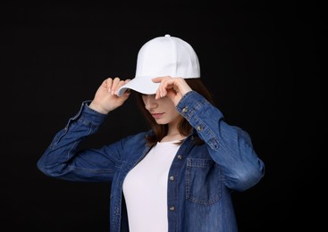 Photo of Young woman wearing stylish white baseball hat on black background