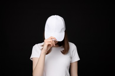 Photo of Young woman wearing stylish white baseball hat on black background