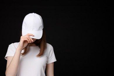 Photo of Young woman wearing stylish white baseball hat on black background, space for text