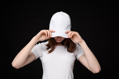 Photo of Young woman wearing stylish white baseball hat on black background