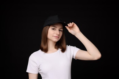 Photo of Young woman wearing stylish baseball hat on black background