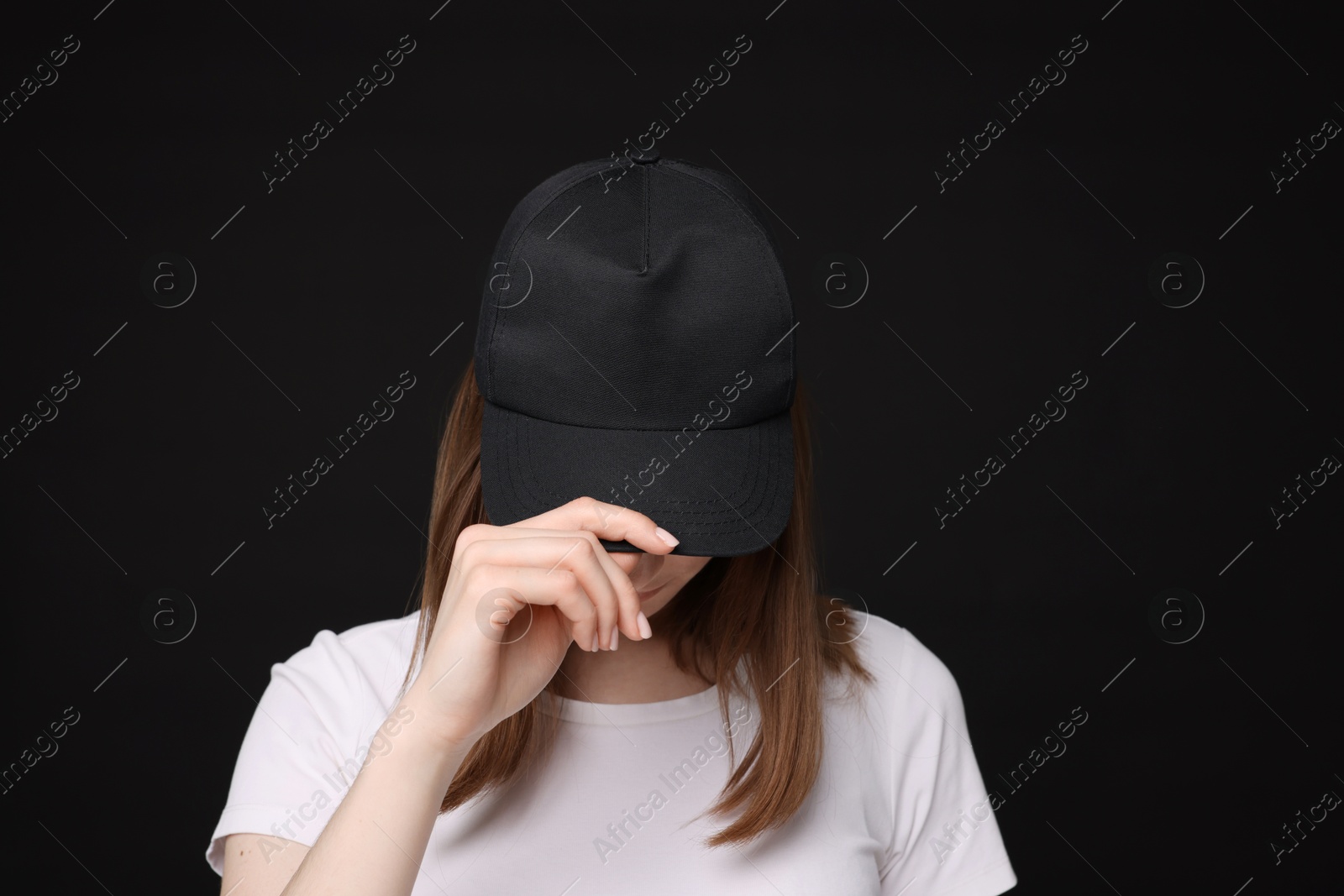 Young woman wearing stylish baseball hat on black background Photo of Young woman wearing stylish baseball hat on black background