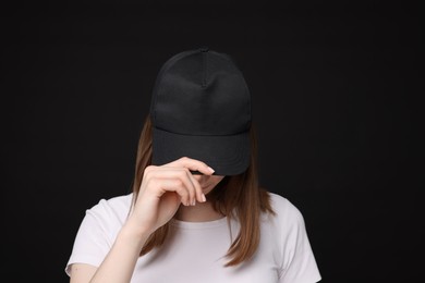 Photo of Young woman wearing stylish baseball hat on black background