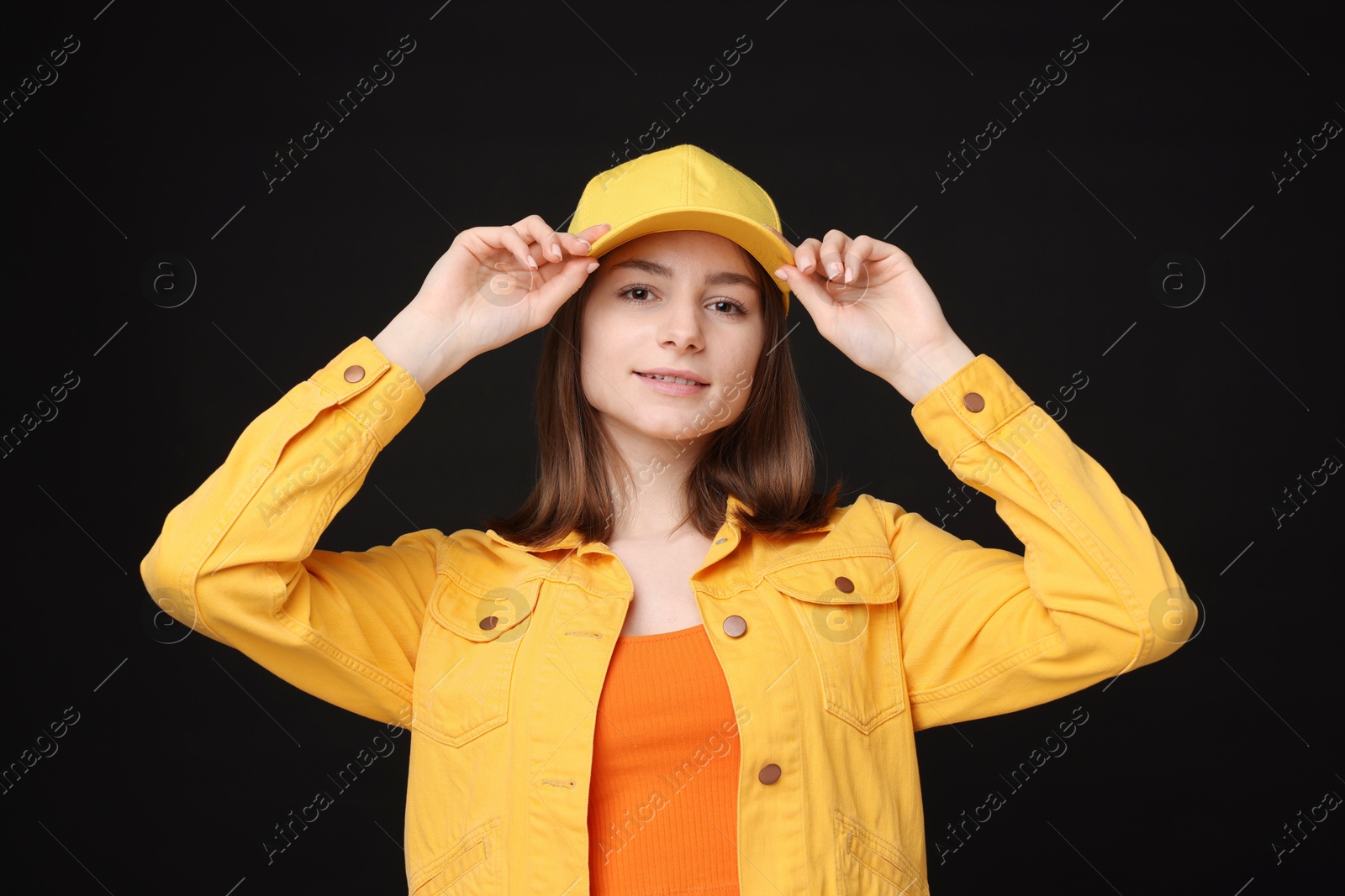 Photo of Young woman wearing stylish yellow baseball hat on black background