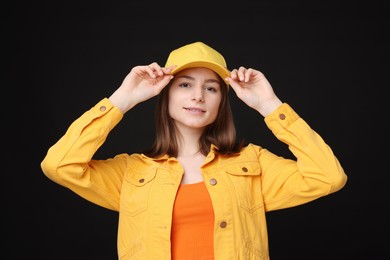 Photo of Young woman wearing stylish yellow baseball hat on black background