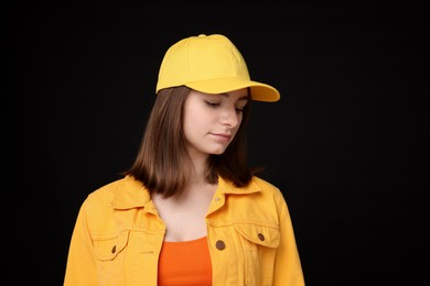 Photo of Young woman wearing stylish yellow baseball hat on black background