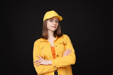 Photo of Young woman wearing stylish yellow baseball hat on black background