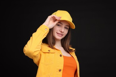 Photo of Young woman wearing stylish yellow baseball hat on black background
