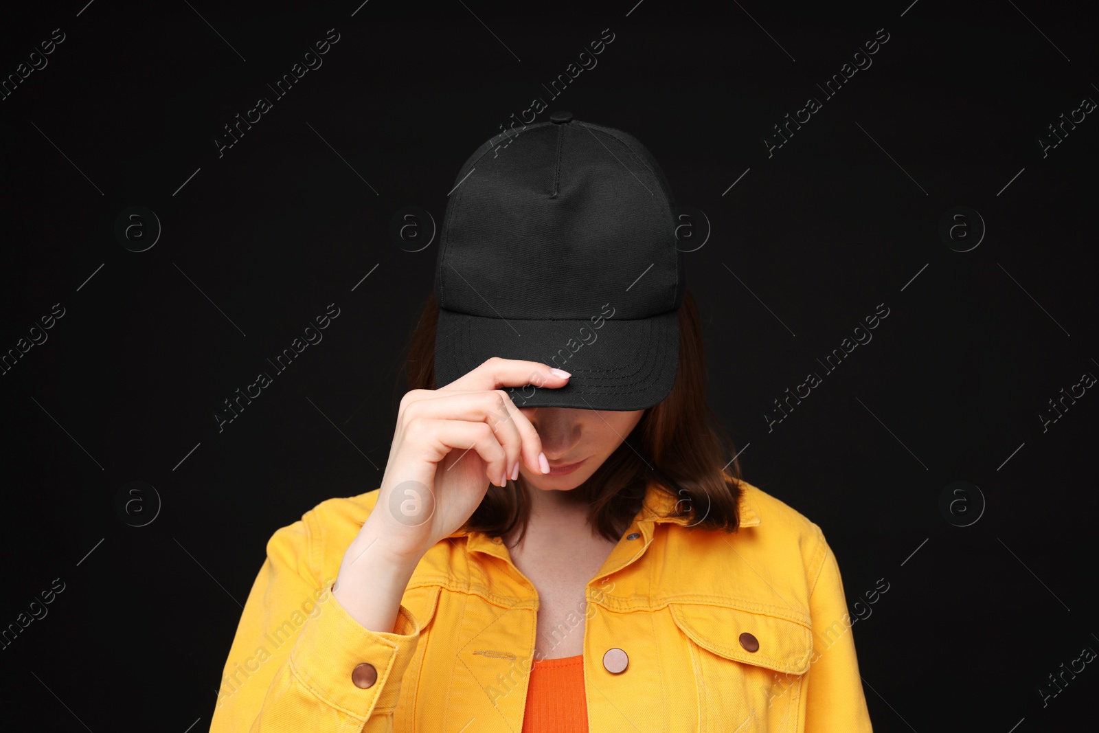 Photo of Young woman wearing stylish baseball hat on black background