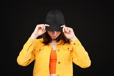 Photo of Young woman wearing stylish baseball hat on black background