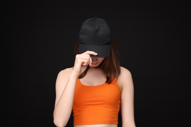 Photo of Young woman wearing stylish baseball hat on black background