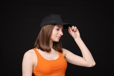 Photo of Young woman wearing stylish baseball hat on black background