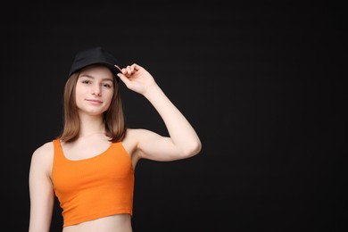 Photo of Young woman wearing stylish baseball hat on black background, space for text