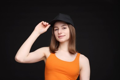 Photo of Young woman wearing stylish baseball hat on black background