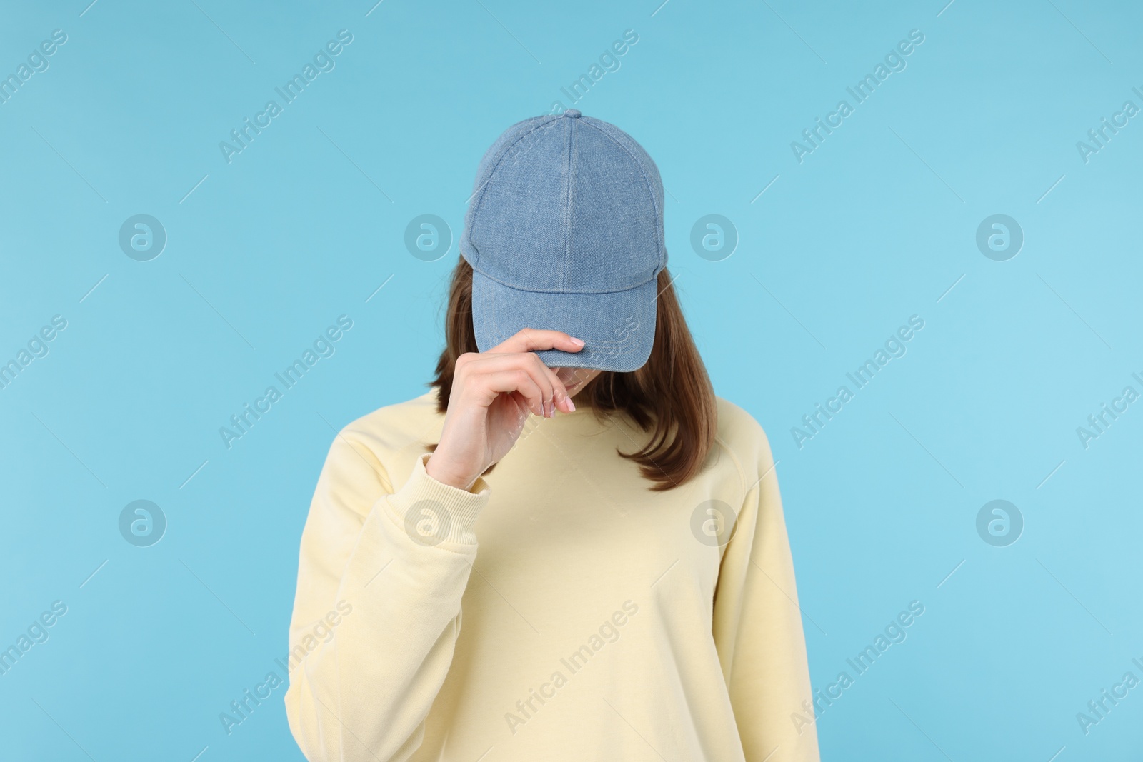 Photo of Young woman wearing stylish denim baseball hat on light blue background