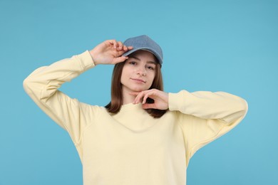 Photo of Young woman wearing stylish denim baseball hat on light blue background