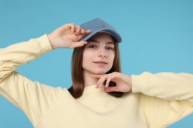 Photo of Young woman wearing stylish denim baseball hat on light blue background