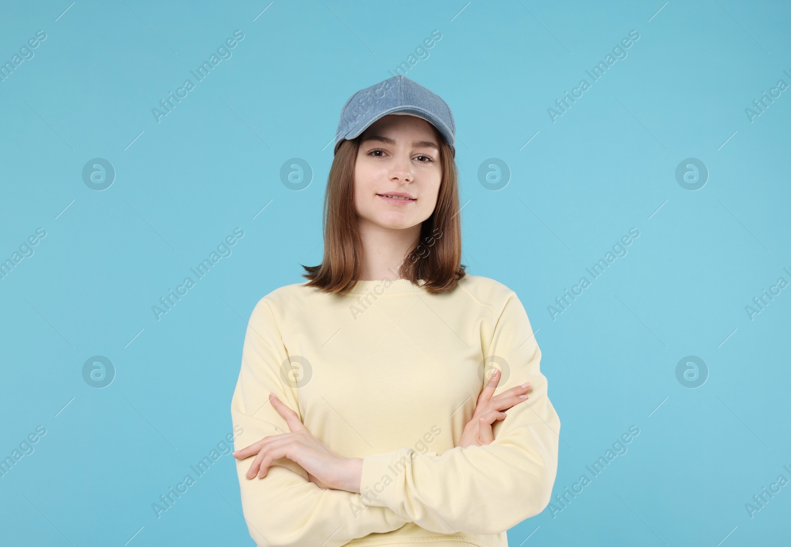 Photo of Young woman wearing stylish denim baseball hat on light blue background