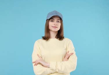 Photo of Young woman wearing stylish denim baseball hat on light blue background