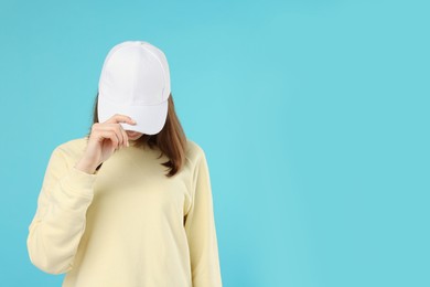 Photo of Young woman wearing stylish white baseball hat on light blue background, space for text